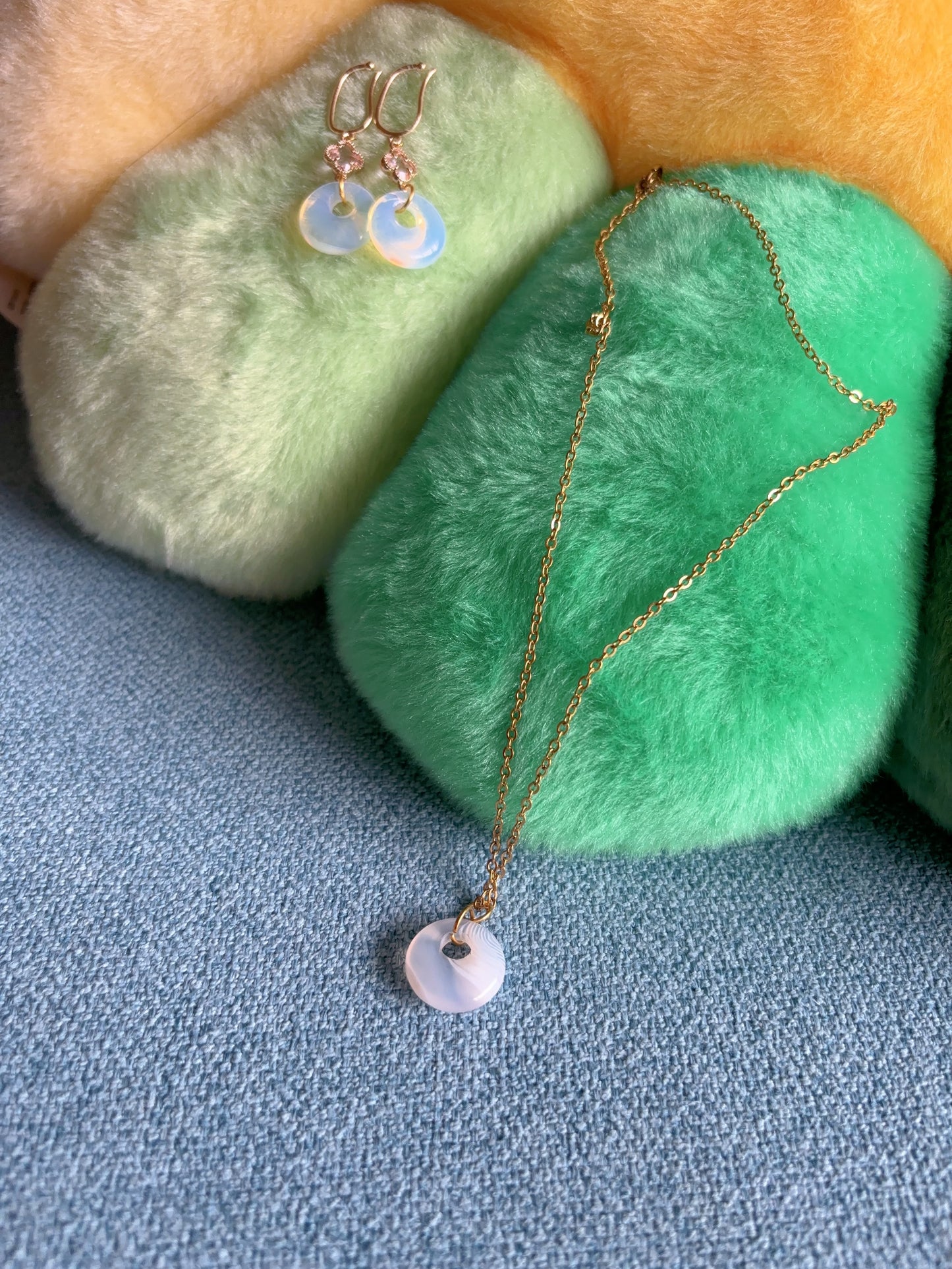 Details of striped agate pendant and opalite earrings showing soft natural patterns and smooth finish