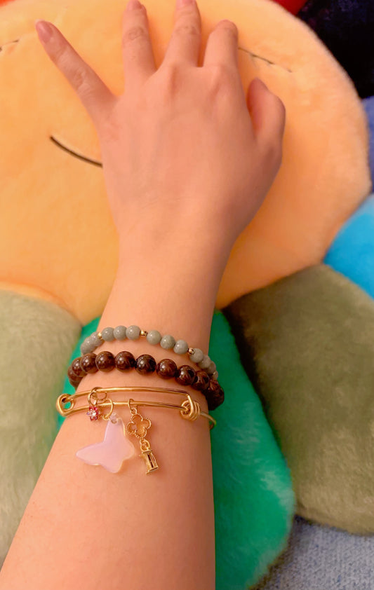 Hand wearing multiple bracelets including the handmade opalite bangle with a colorful background