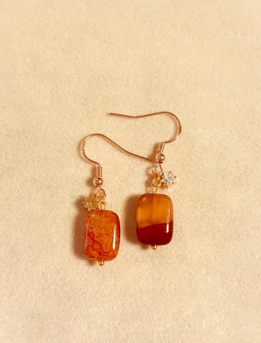 Natural red agate gemstone earrings close up showing warm amber tones and unique stone texture
