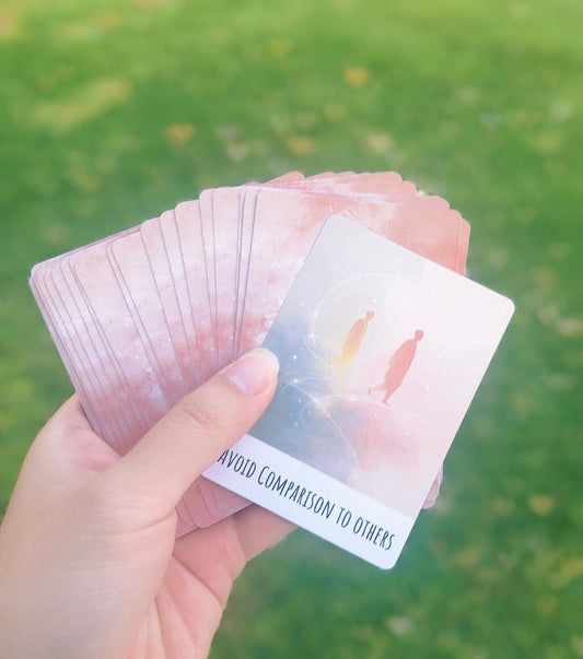 Pocket ritual oracle cards spread in hand showing soft pastel illustrations