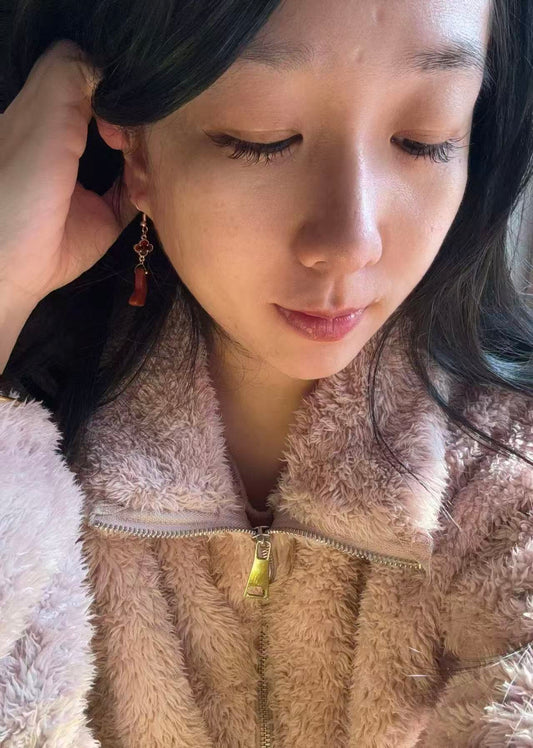 Woman wearing red jasper butterfly earrings with clover charm, soft natural lighting