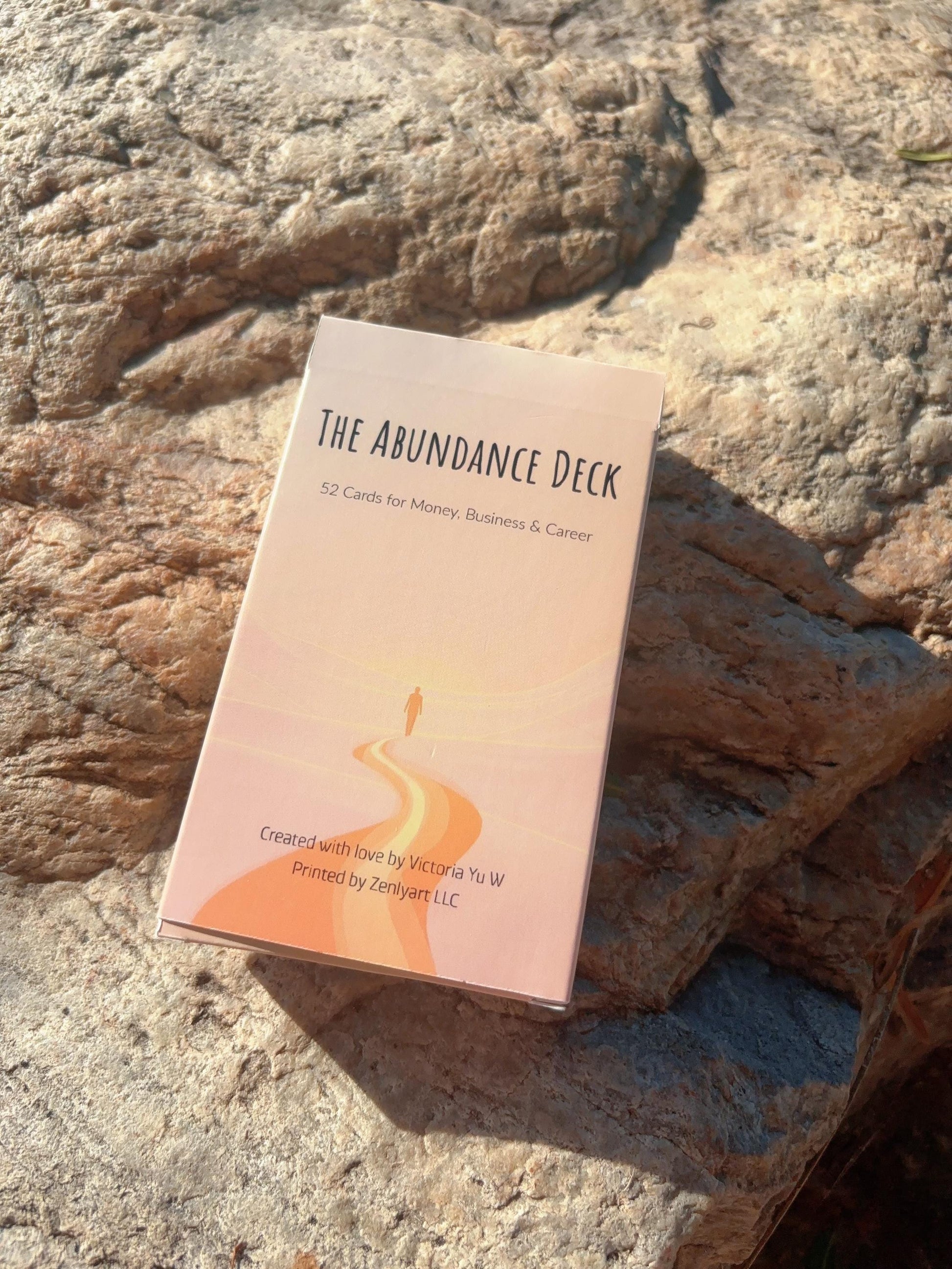 Abundance Oracle Deck box placed on natural stone in warm sunlight