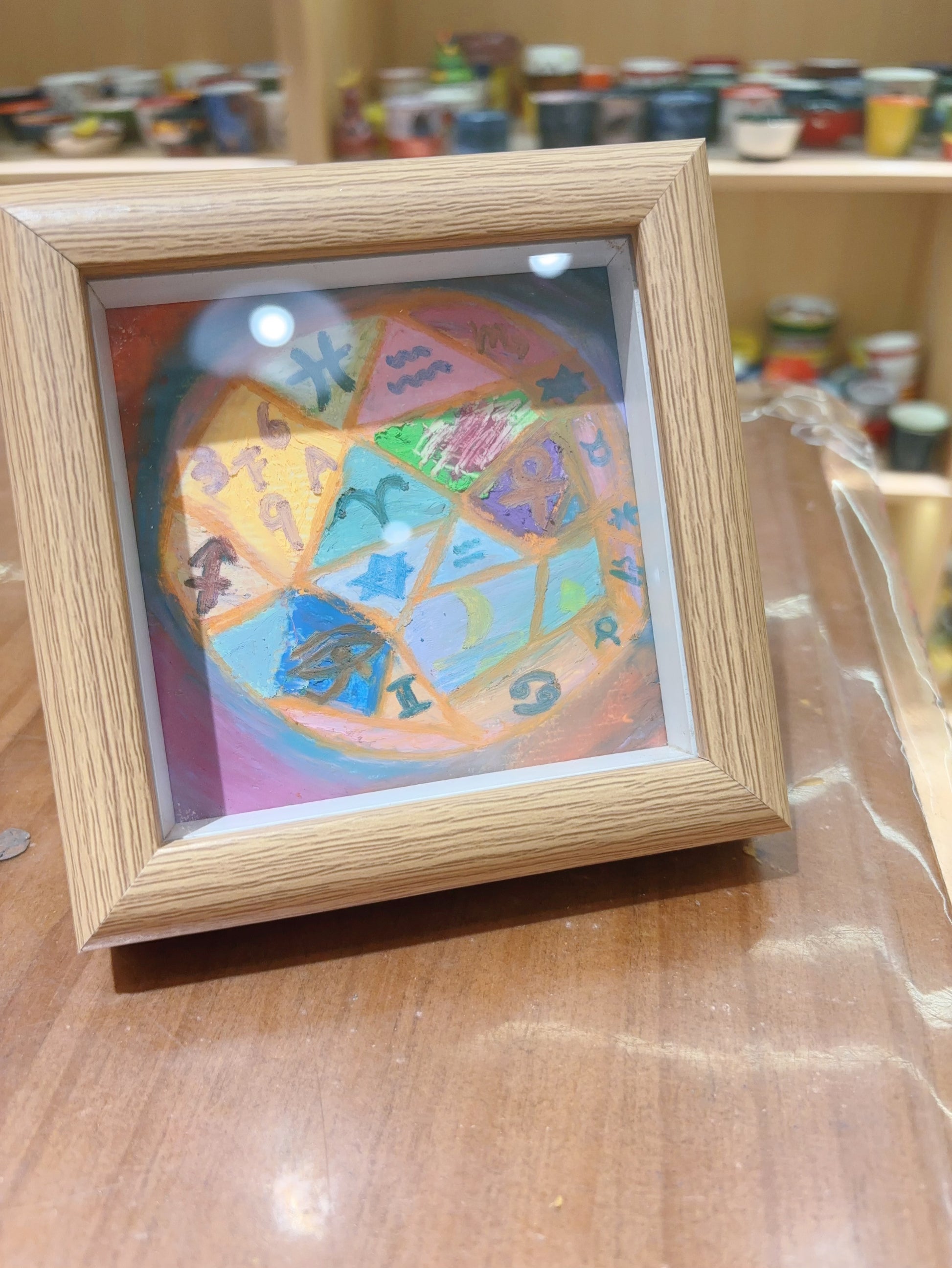 Angled view of framed mini cosmos painting with soft pastel colors and symbols