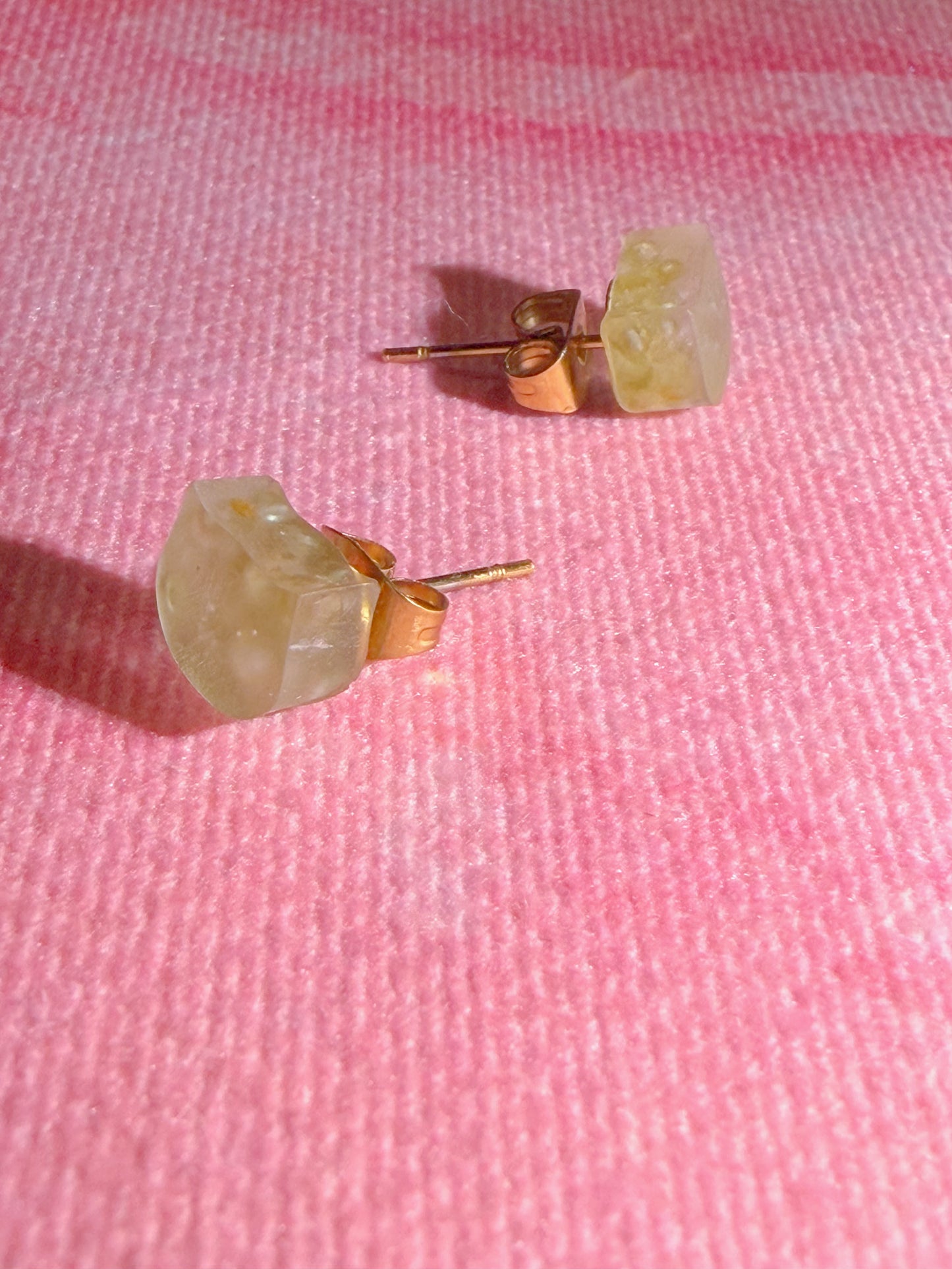 Angled view of peridot stud earrings with matte finish and gold tone backing