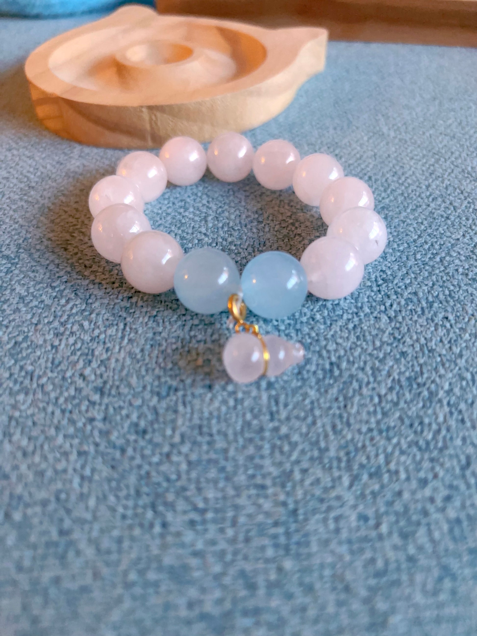 Beaded crystal bracelet with large light blue and pink beads flay lay soft aesthetic a textured blue surface