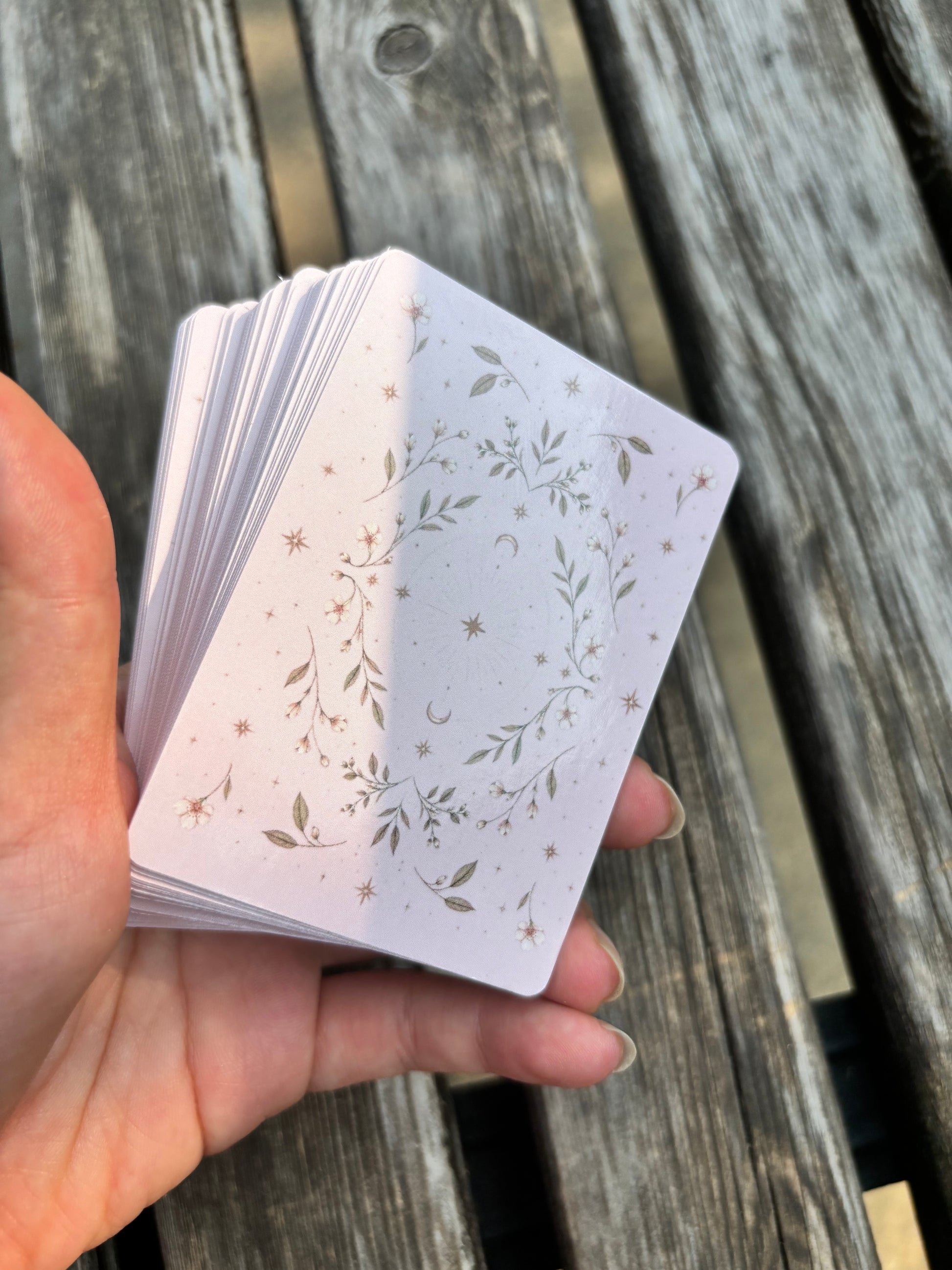 Close-up of The Fruit Deck card backs featuring celestial line art and pastel pink design.