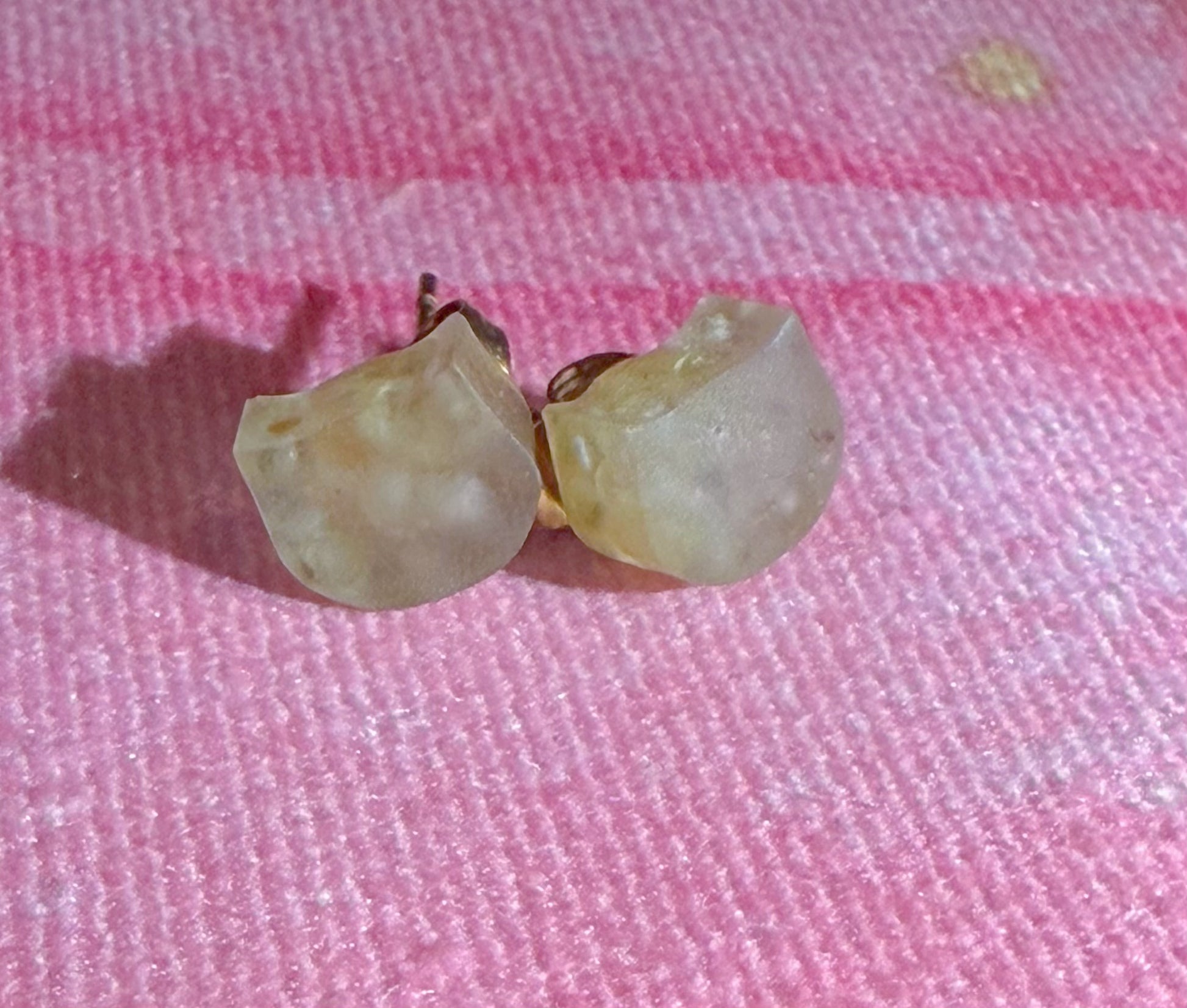 Close-up of small peridot stud earrings with soft green tone and natural inclusions