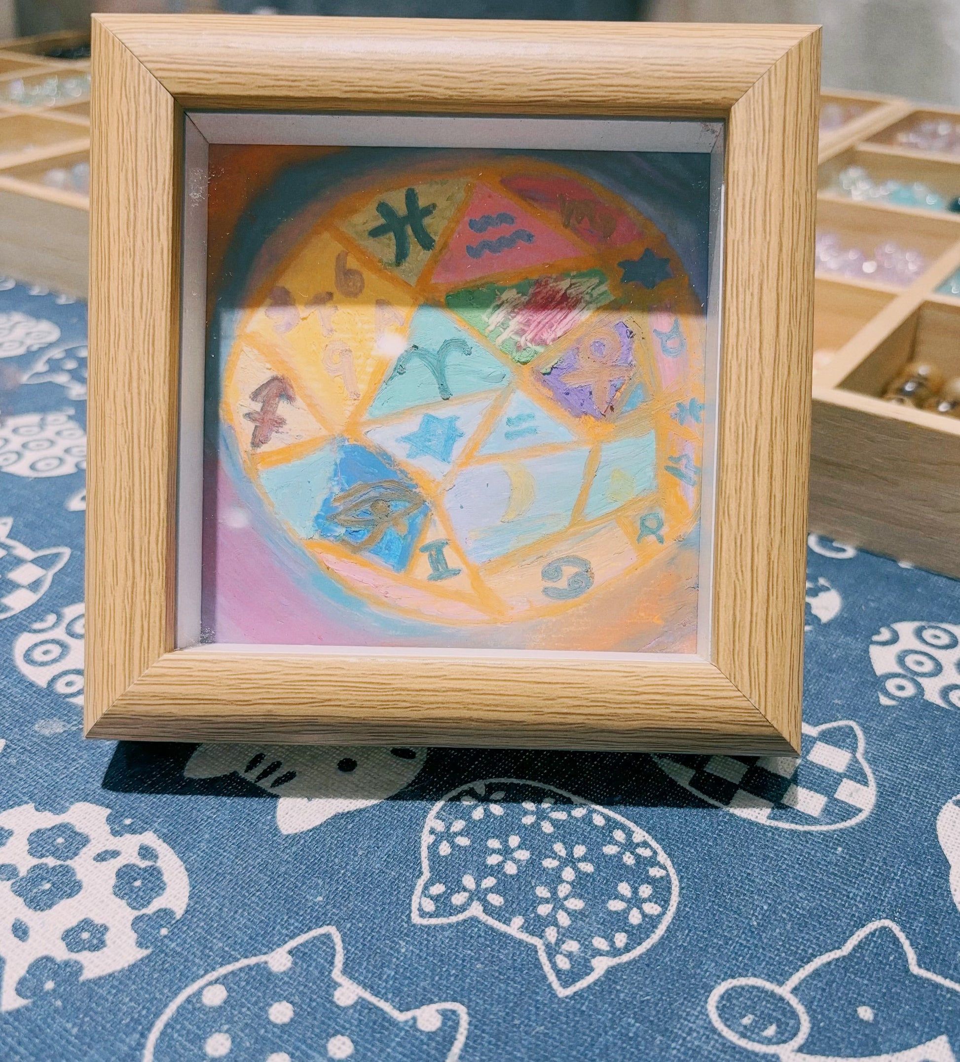 Framed intuitive abstract painting with colorful symbolic wheel design on table