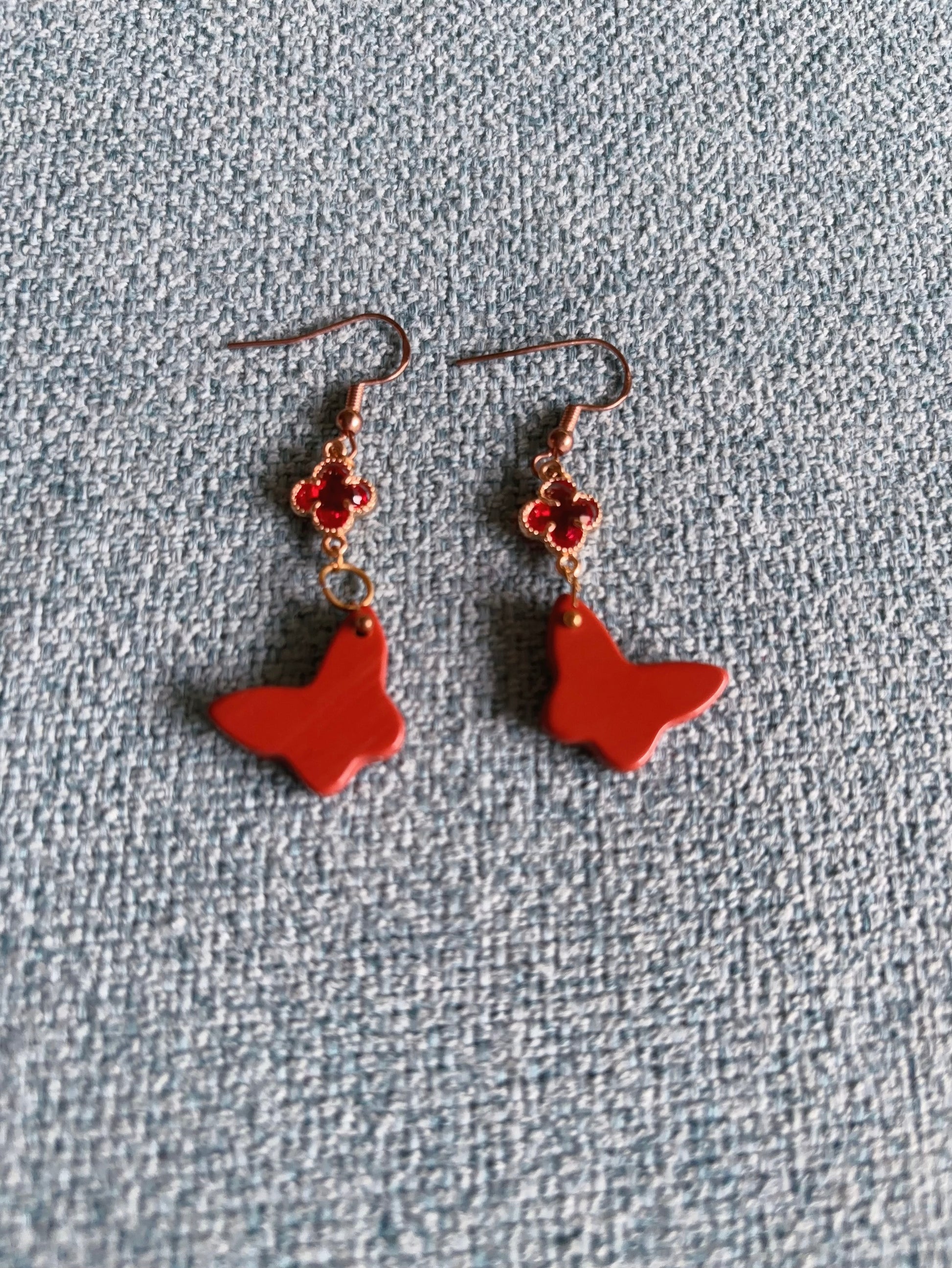 Handmade red jasper butterfly earrings with gold clover charm and hook design