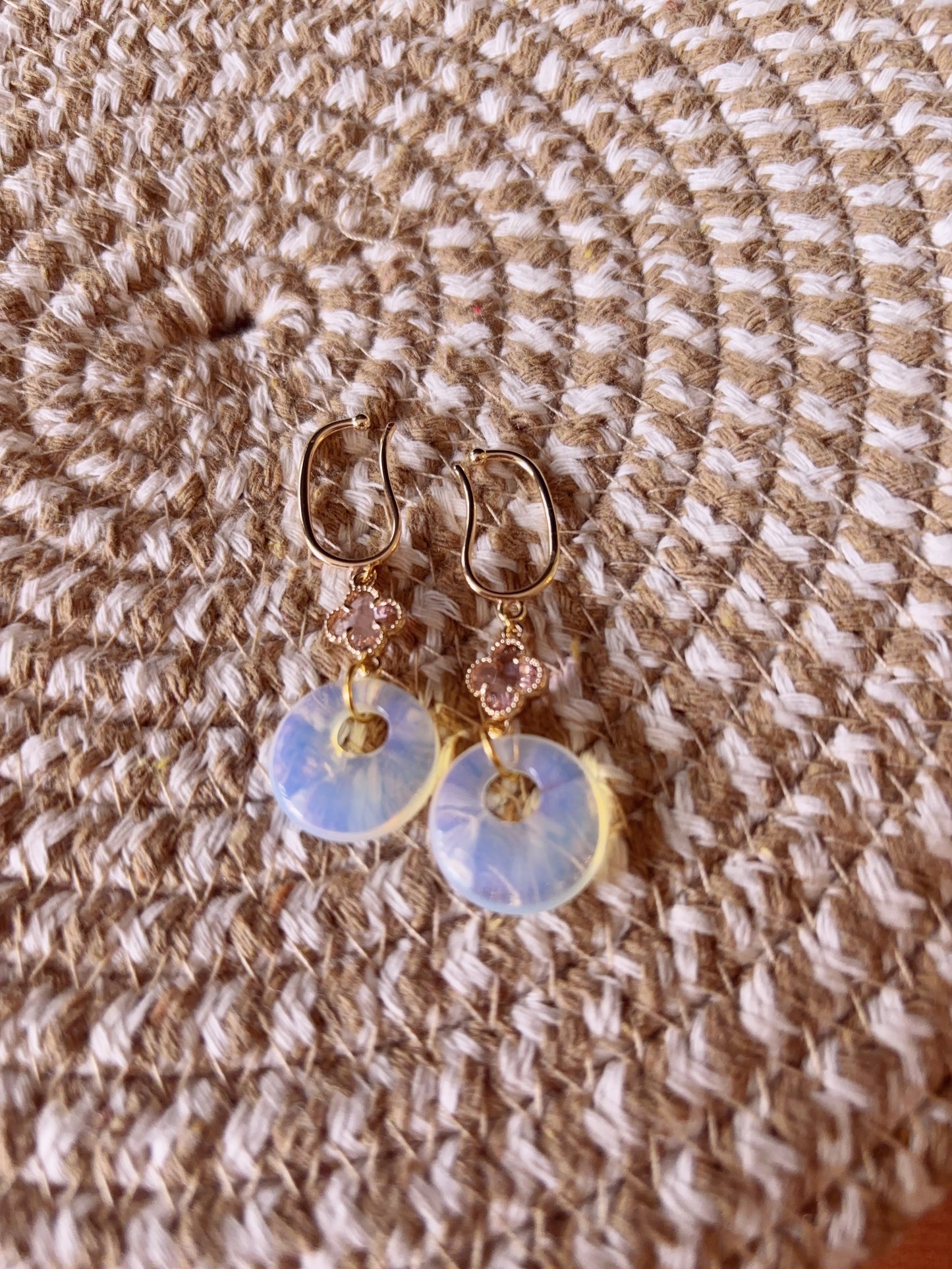 Opalite clip-on earrings with clover charm and 14k gold base on a textured fabric background