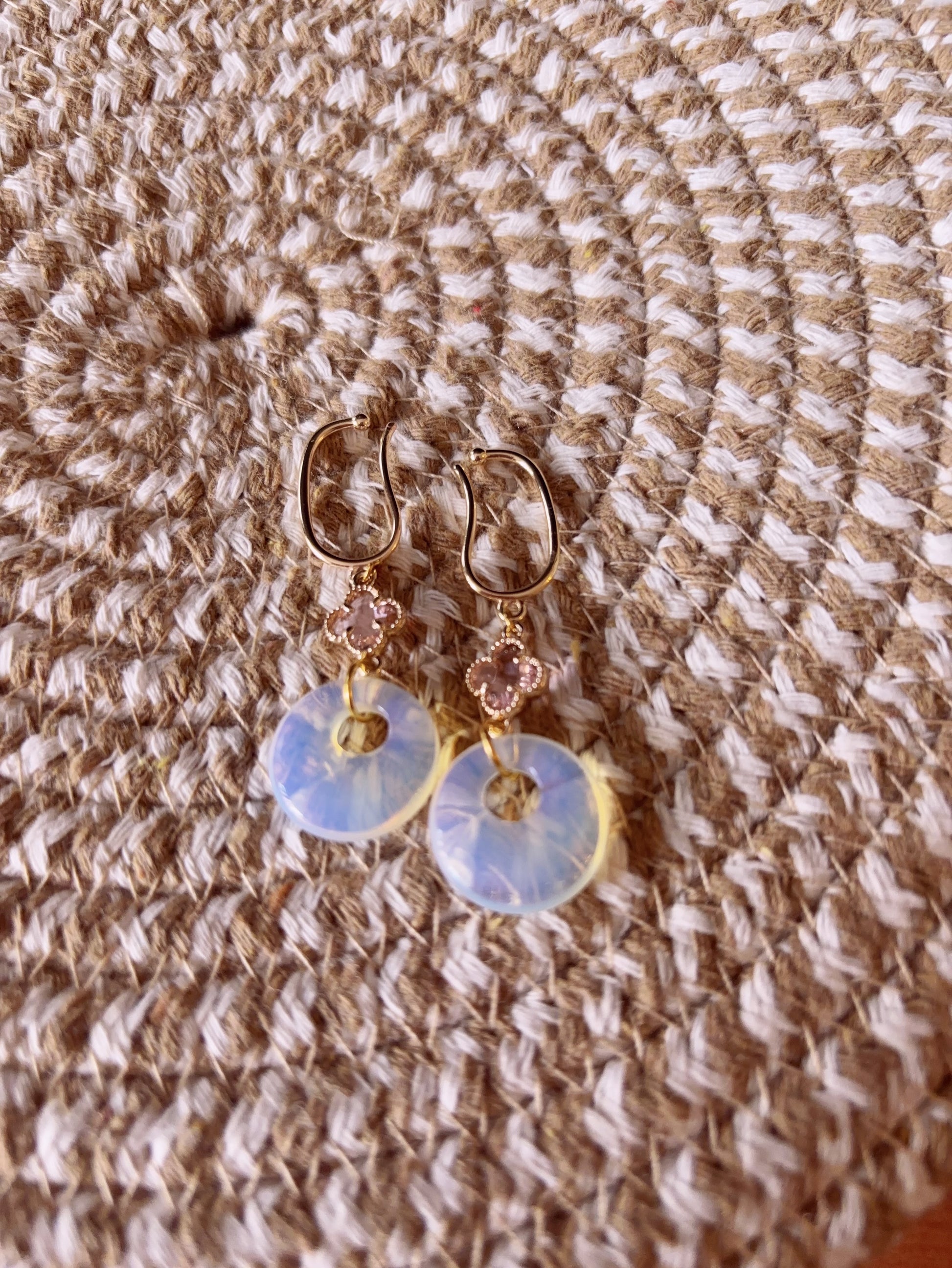 Opalite clip-on earrings with clover charm and 14k gold base on a textured fabric background
