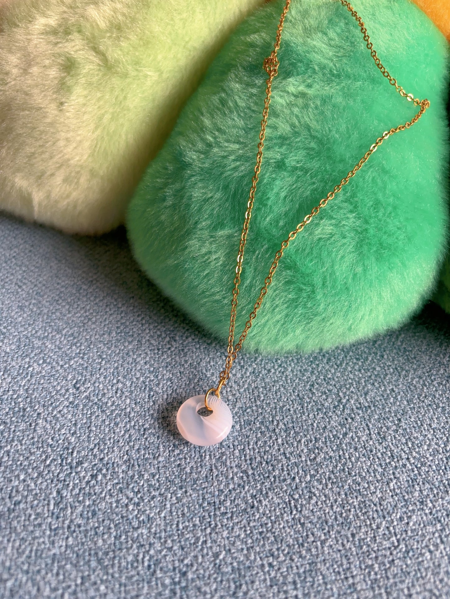 Striped agate round coin shape pendant necklace with gold chain on neutral background