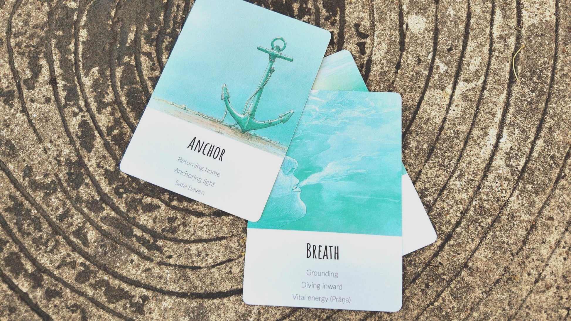 Two cards from Ocean Healing Deck with anchor and breath illustrations on a textured surface