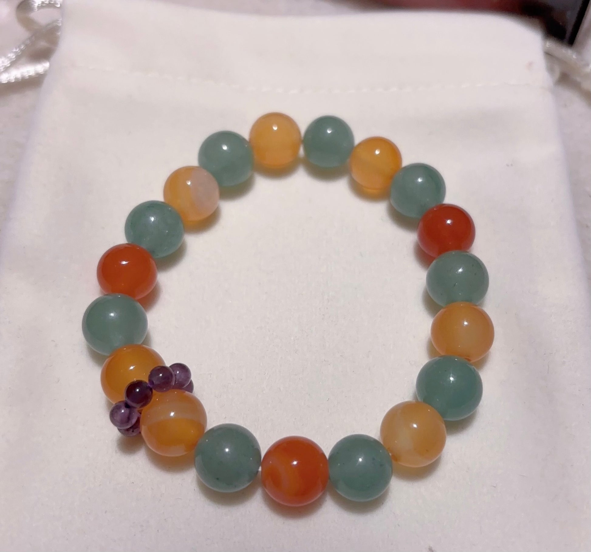 green aventurine and red agate bracelet with amethyst accent flat lay on soft fabric