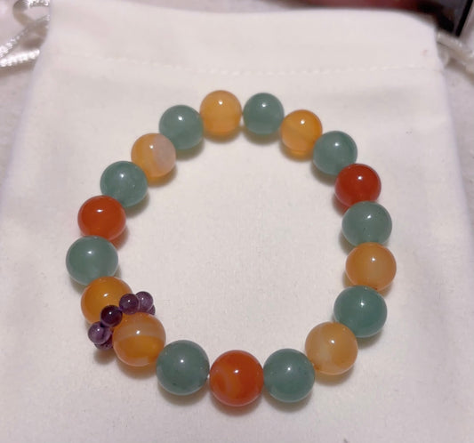 green aventurine and red agate bracelet with amethyst accent flat lay on soft fabric