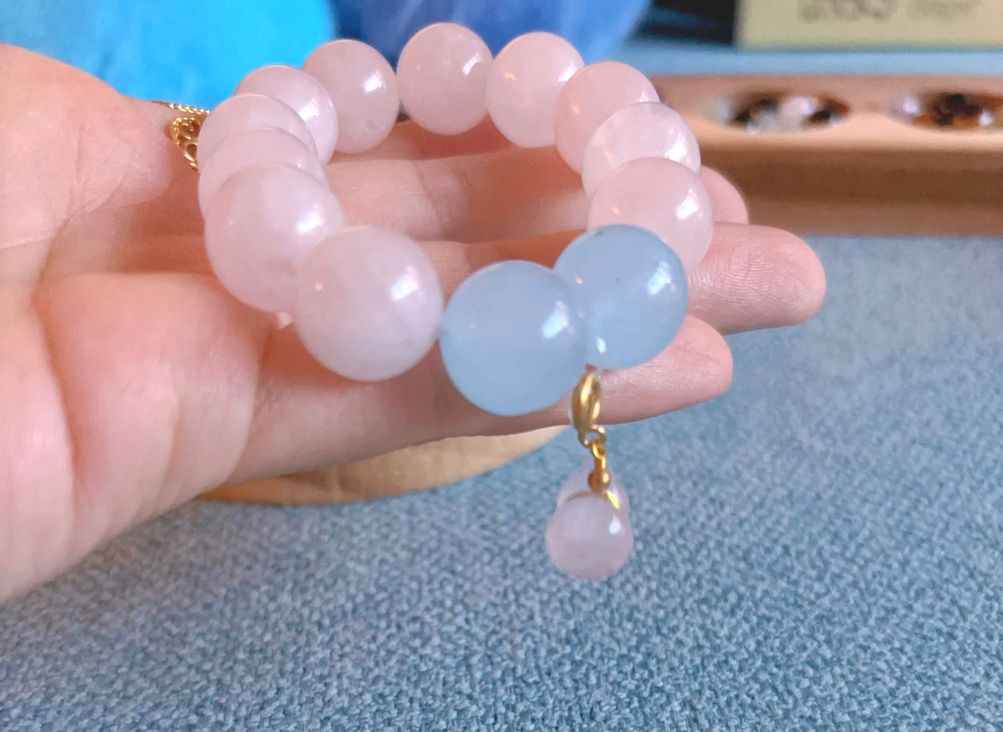 hand holding rose quartz and aquamarine bracelet close up