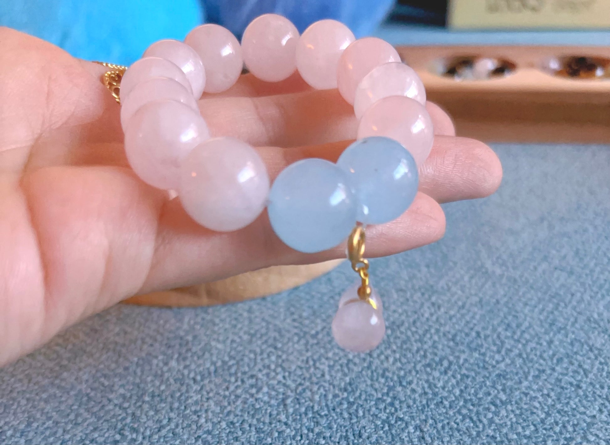 hand holding rose quartz and aquamarine bracelet close up